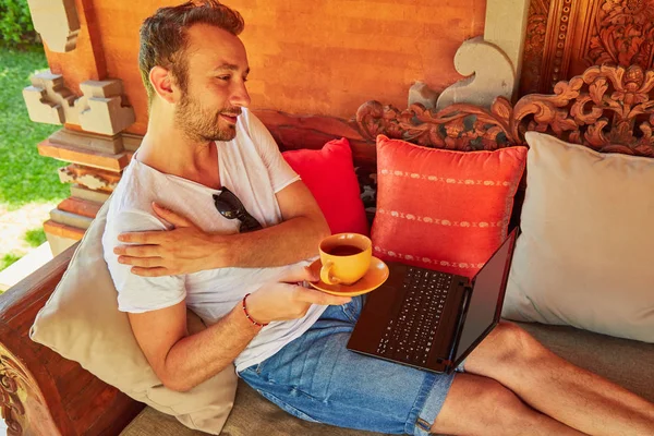 Man with coffee / tea and laptop on a home porch. — Stock Photo, Image