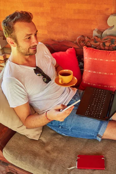 Hombre con café / té y portátil en un porche de casa . — Foto de Stock