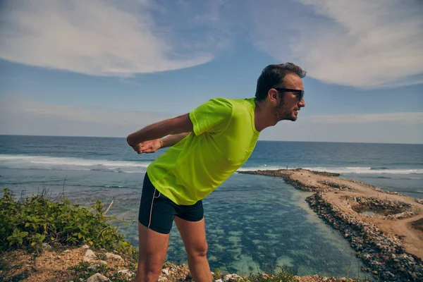 Sportivo che si estende su una scogliera esotica tropicale vicino all'oceano . — Foto Stock