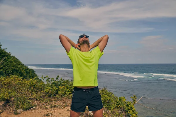 Sportsman stretching op een tropische exotische klif in de buurt van de Oceaan. — Stockfoto