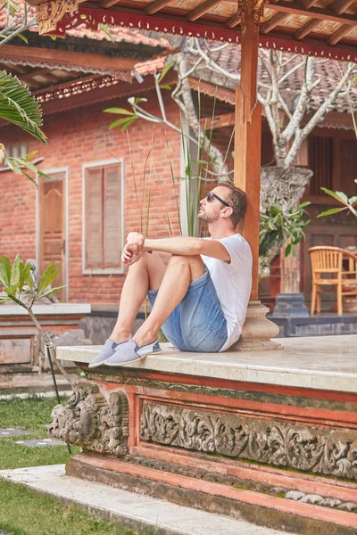 Hombre sentado en un patio / porche de la casa y disfrutar del verano . — Foto de Stock