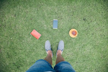 Akıllı telefon, fincan od kahve / çay ve dizüstü bilgisayar ile adam bir çim