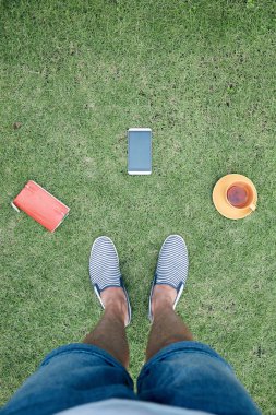 Akıllı telefon, fincan od kahve / çay ve dizüstü bilgisayar ile adam bir çim