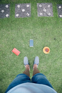 Akıllı telefon, fincan od kahve / çay ve dizüstü bilgisayar ile adam bir çim