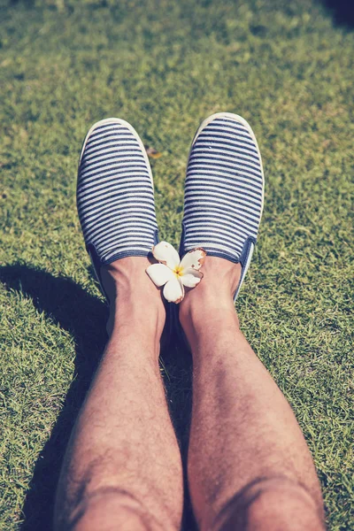 Pés de homem com flores de frangipani no gramado verde . — Fotografia de Stock