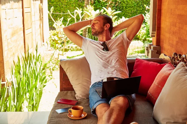 Man with coffee / tea and laptop on a home porch. — Stock Photo, Image
