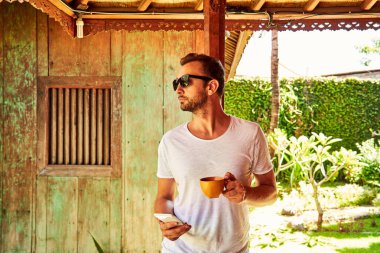 Bir evin önündeki verandada cellpohne kullanan adam.