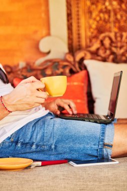 Bir ev verandada kahve / çay ve dizüstü bilgisayar ile Man.