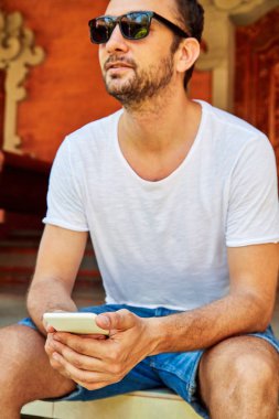 Bir evin önündeki verandada cellpohne kullanan adam.