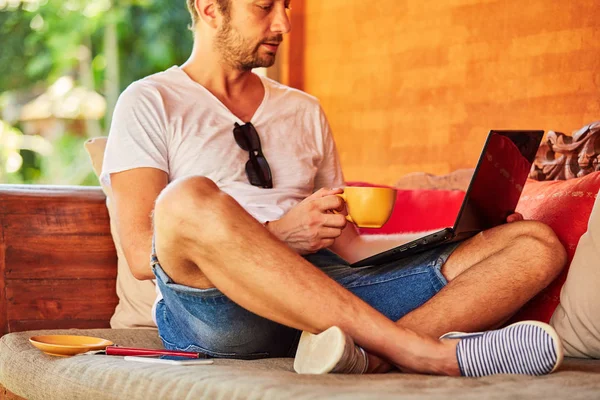 Bir ev verandada kahve / çay ve dizüstü bilgisayar ile Man.