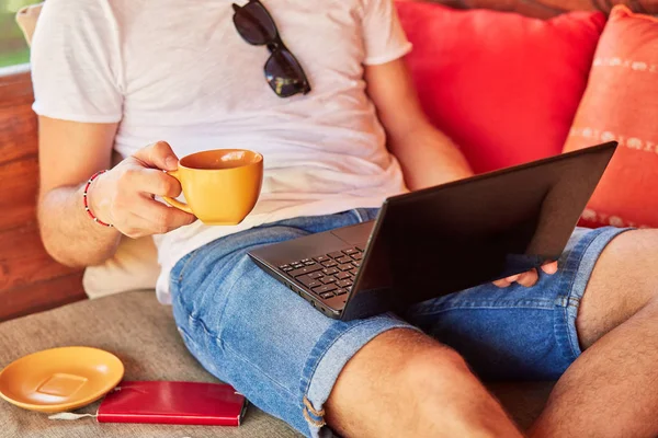 Bir ev verandada kahve / çay ve dizüstü bilgisayar ile Man.