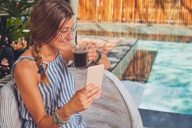 Bir terasta cep telefonu kullanarak gözlüklü sevimli kız.