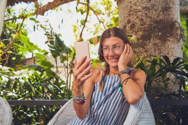 Bir terasta cep telefonu kullanarak gözlüklü sevimli kız.