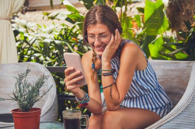 Bir terasta cep telefonu kullanarak gözlüklü sevimli kız.