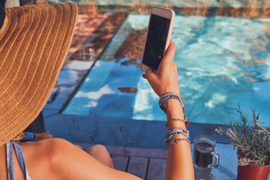 Bir yüzme havuzu güverte salonda yatarken cep telefonu kullanarak kız 