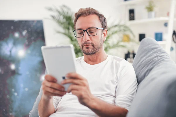 Hombre usando tableta y sufring en el Internet en su sala de estar . — Foto de Stock