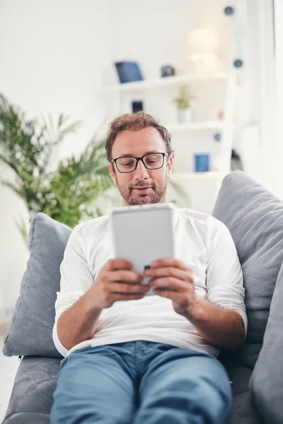 Hombre usando tableta y sufring en el Internet en su sala de estar . — Foto de Stock