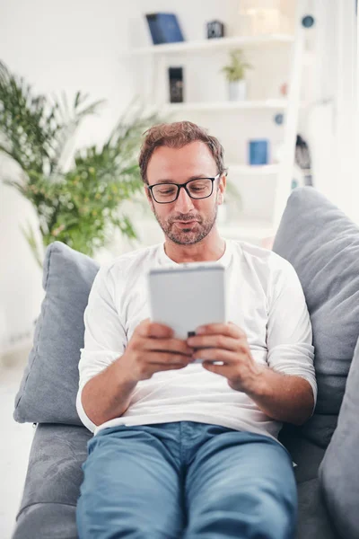 Hombre usando tableta y sufring en el Internet en su sala de estar . — Foto de Stock