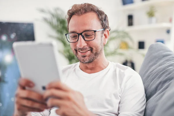 Hombre usando tableta y sufring en el Internet en su sala de estar . — Foto de Stock