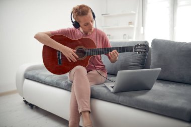 Gitarist dizüstü bilgisayarda internet video dersleri ve özel dersler izliyor..