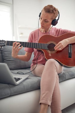 Gitarist dizüstü bilgisayarda internet video dersleri ve özel dersler izliyor..