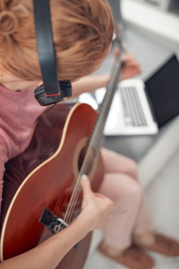 Gitarist dizüstü bilgisayarda internet video dersleri ve özel dersler izliyor..