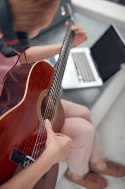 Gitarist dizüstü bilgisayarda internet video dersleri ve özel dersler izliyor..