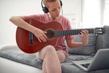Gitarist dizüstü bilgisayarda internet video dersleri ve özel dersler izliyor..