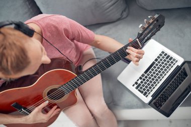 Gitarist dizüstü bilgisayarda internet video dersleri ve özel dersler izliyor..