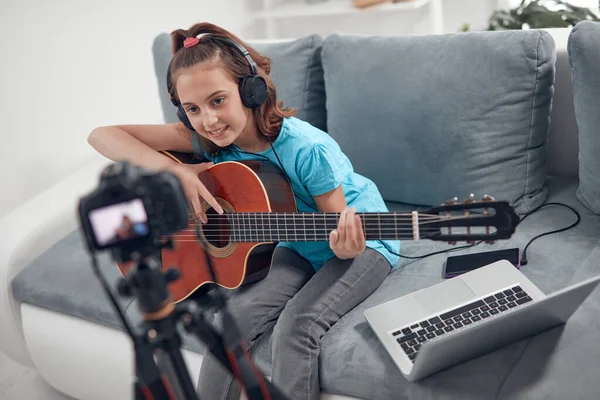 Child guitarist making video lessons and tutorials for internet vlog website classes.