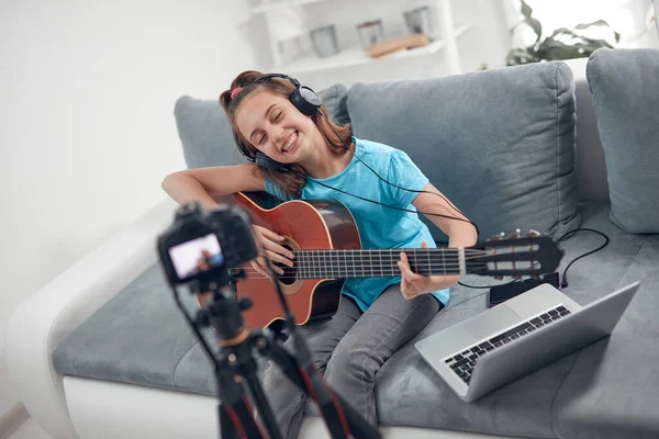 Child guitarist making video lessons and tutorials for internet vlog website classes.