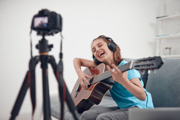 Child guitarist making video lessons and tutorials for internet vlog website classes.