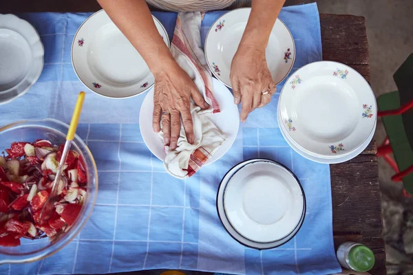 Woman preparing food and feast for summertime lunch at countryside rustic cottage outdoor kitchen.