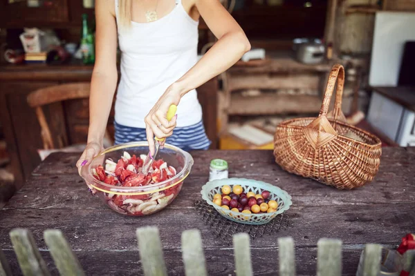 Woman preparing food and feast for summertime lunch at countryside rustic cottage outdoor kitchen.