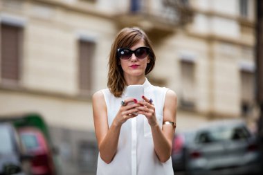 Caddenin ortasında akıllı telefon kullanan bir kadın..