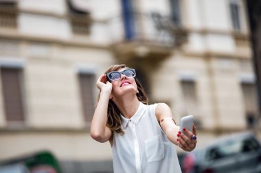 Caddenin ortasında akıllı telefon kullanan bir kadın..