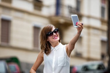 Caddenin ortasında akıllı telefon kullanan bir kadın..