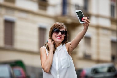 Caddenin ortasında akıllı telefon kullanan bir kadın..