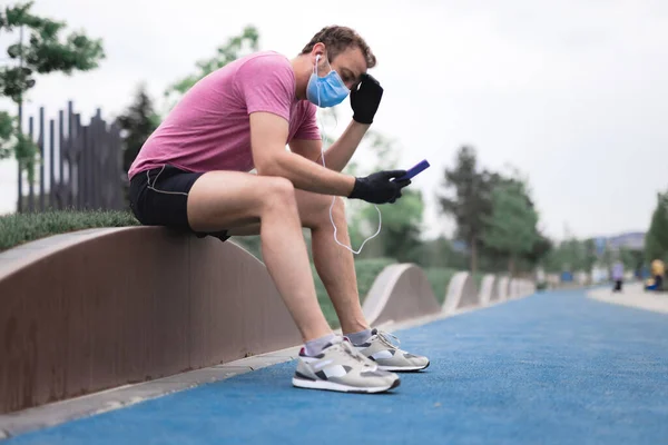 Deportista Con Máscara Médica Guantes Smartphone Auriculares Trabajando Trotando Entorno —  Fotos de Stock