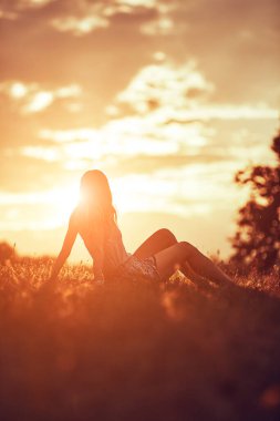 Tarlada oturan bir kadının silueti..