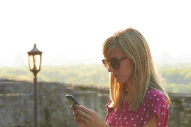 Kentsel çevrede modern akıllı telefon kullanan genç bir kadın.