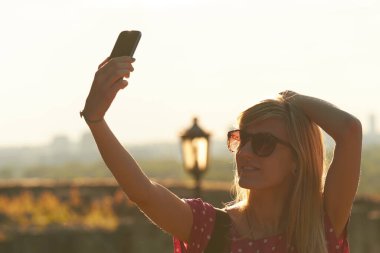 Kentsel çevrede modern akıllı telefon kullanan genç bir kadın.