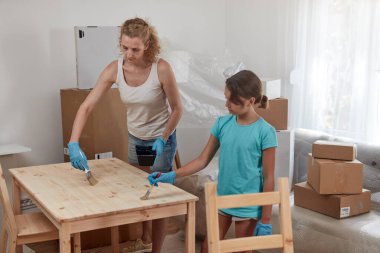 Anne ve kız yeni dairede mobilya boyayıp montajlıyorlar, taşınıyorlar ve çalışkan oluyorlar..