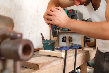 Erkek marangoz antika bir atölyede eski ahşap üzerinde çalışıyor..