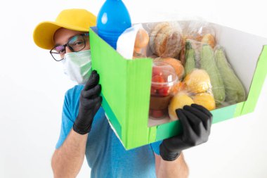 Koruyucu maskeli teslimatçı. Bakkaliye kutusuyla birlikte..