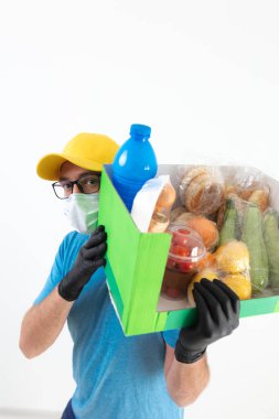 Koruyucu maskeli teslimatçı. Bakkaliye kutusuyla birlikte..