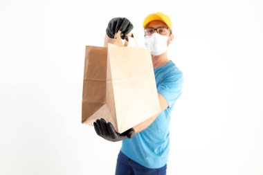 Koruyucu maskeli teslimatçı. Elinde poşet dolusu yiyecek var..