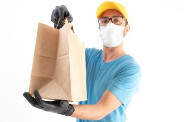 Koruyucu maskeli teslimatçı. Elinde poşet dolusu yiyecek var..