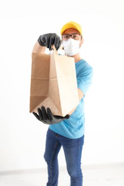 Koruyucu maskeli teslimatçı. Elinde poşet dolusu yiyecek var..