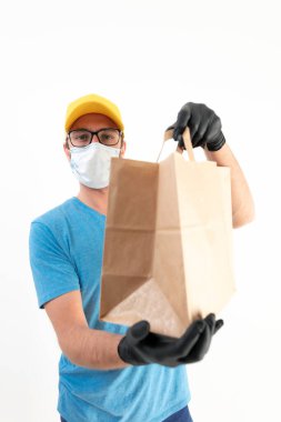 Koruyucu maskeli teslimatçı. Elinde poşet dolusu yiyecek var..